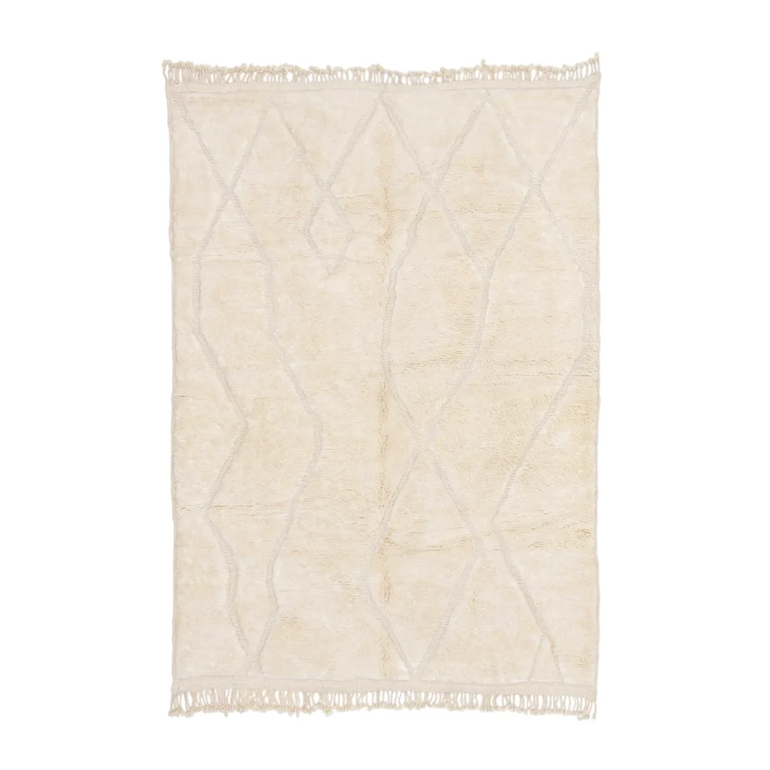 A cream-colored area rug with a subtle, irregular geometric pattern and fringed edges on the shorter sides.