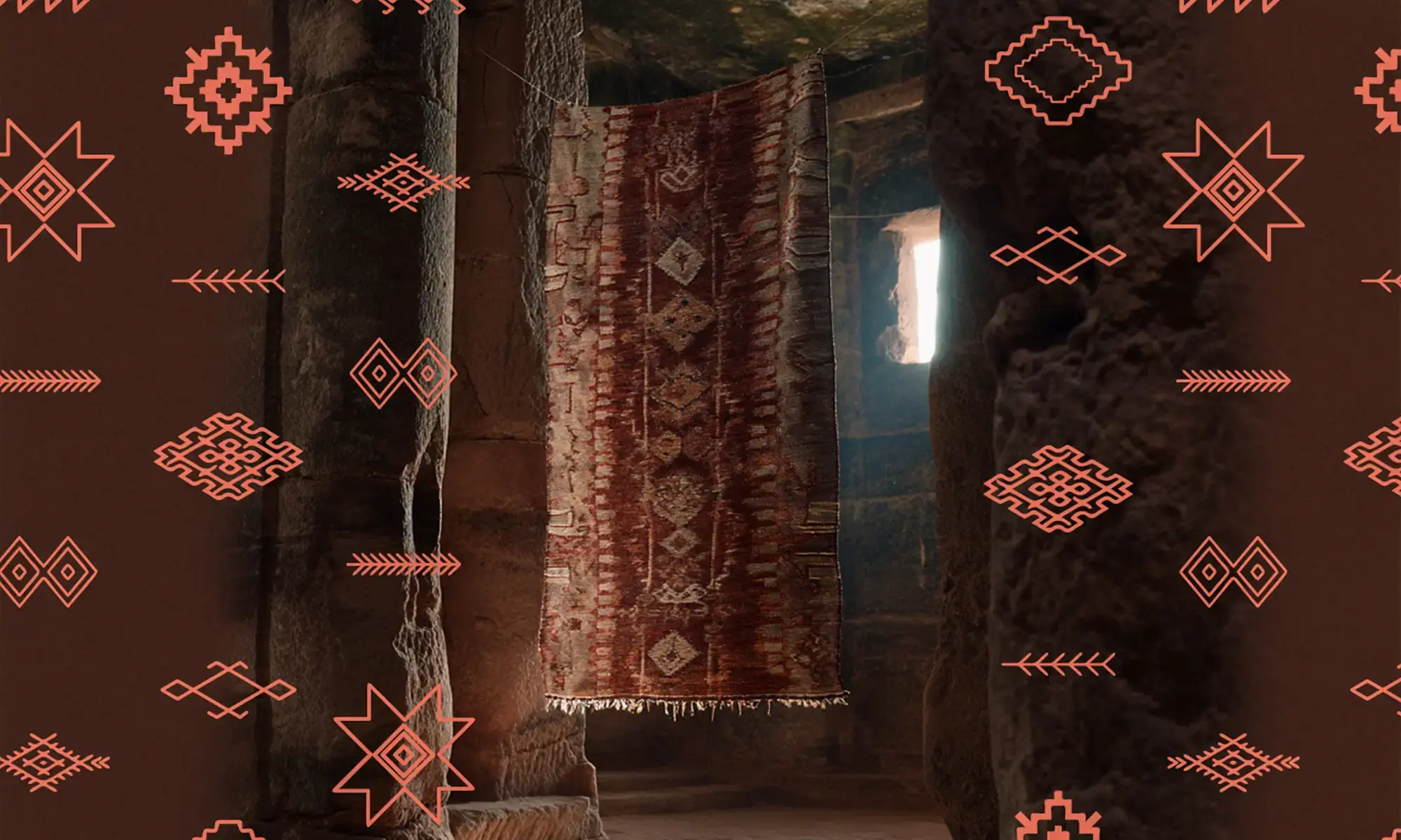 An Artisanal Rug with red and beige patterns hangs in a stone-walled room, framed by geometric motifs overlaid on the sides of the image.