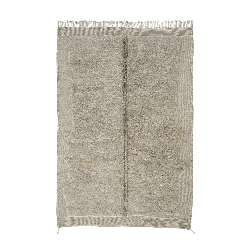 A rectangular hand-knotted artisanal wool rug in neutral tones with a textured central area, a subtle vertical line, and fringes along the shorter edges.