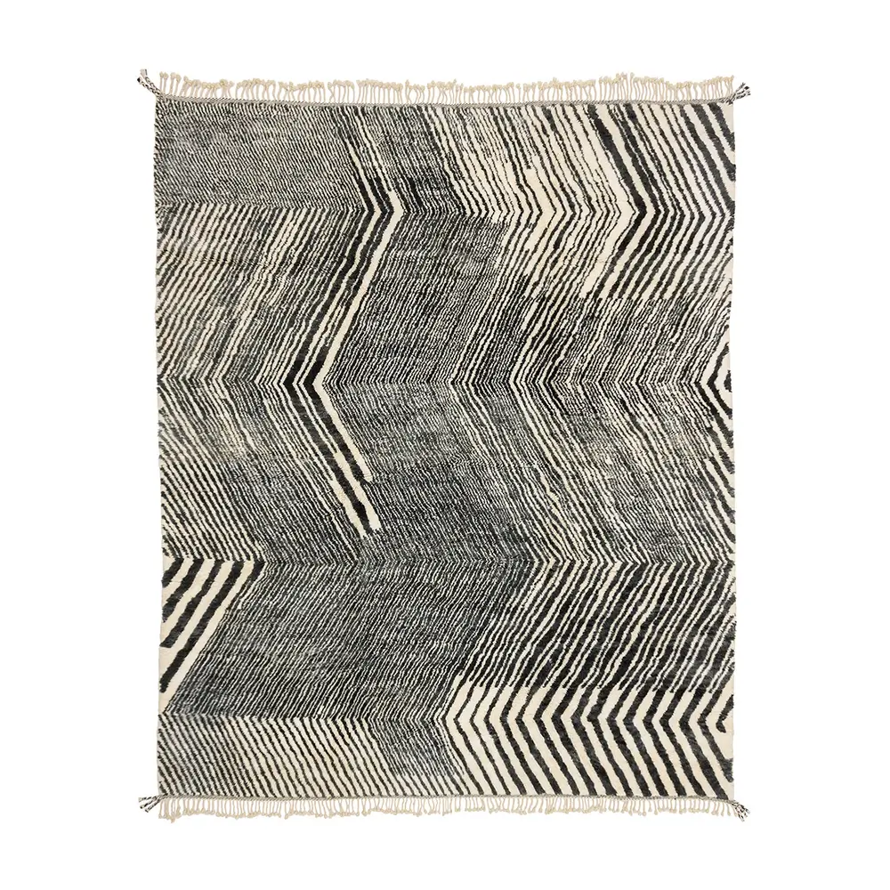 Discover the elegance of a hand-knotted rug featuring a black and white zigzag pattern with fringed edges. This handmade home decor piece adds sophistication and style to any room.