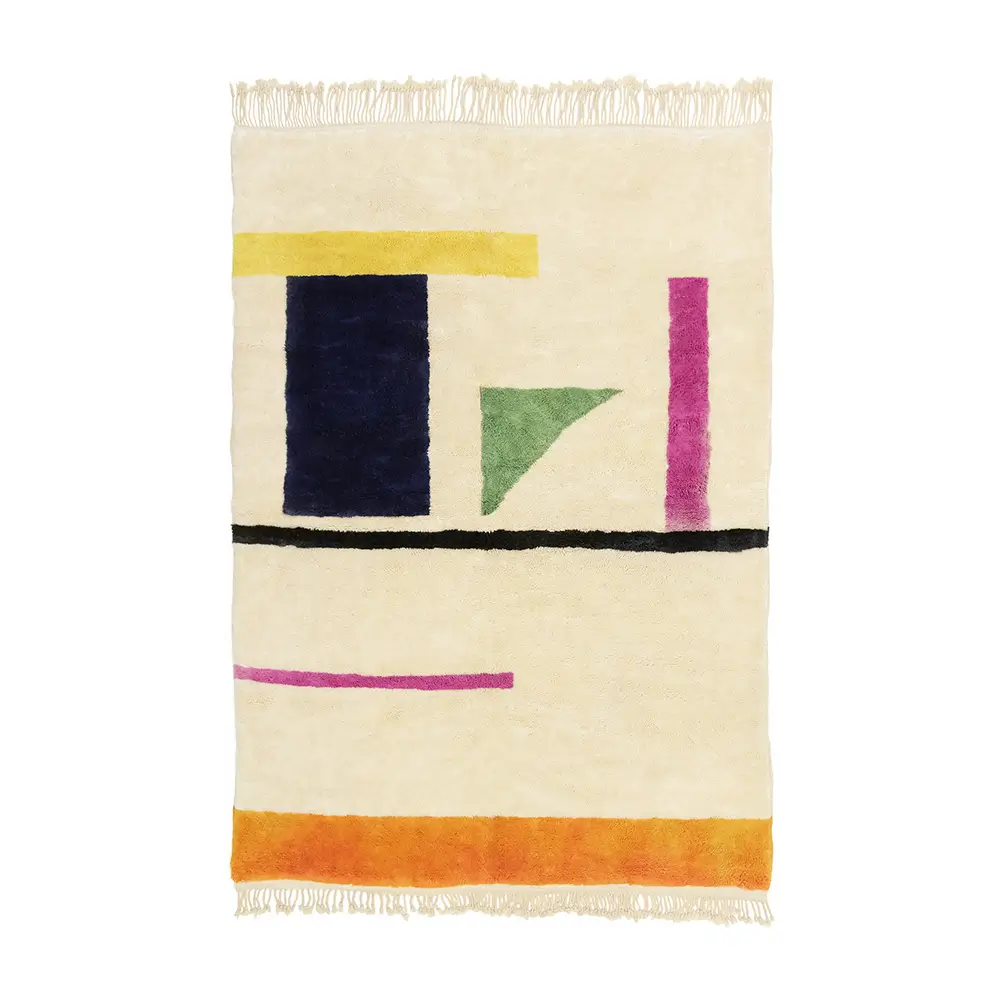 A beige rug with abstract geometric shapes in blue, yellow, green, pink, and orange, featuring fringe on the edges.